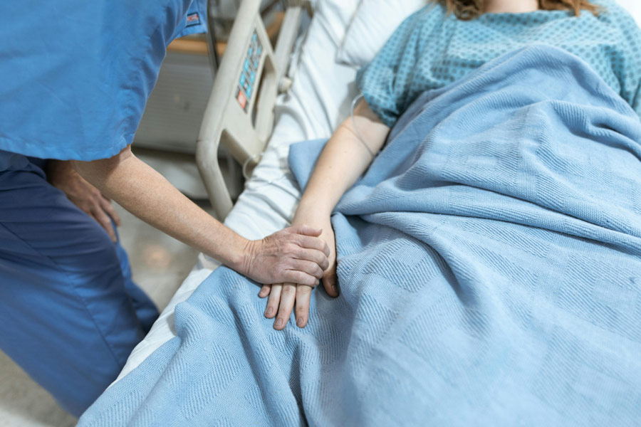 Nurse holding the hand of a patient lying in bed