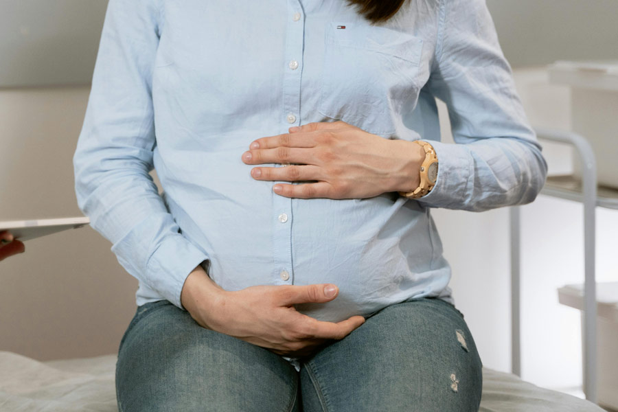 A pregnant individual holding their stomach