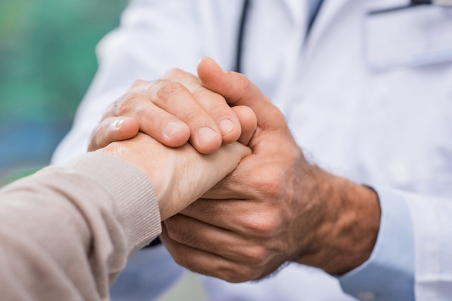 A patient and doctor holding hands.